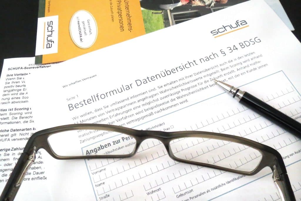 Schufa-Auskunft Bild mit Brille und Kugelschreiber