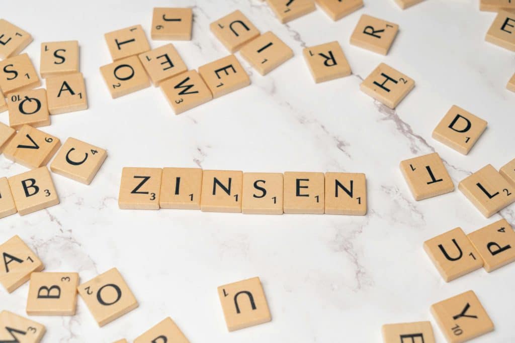 Spielsteine mit Buchstaben auf die nebeneinander das Wort "Zinsen" zu sehen ist.